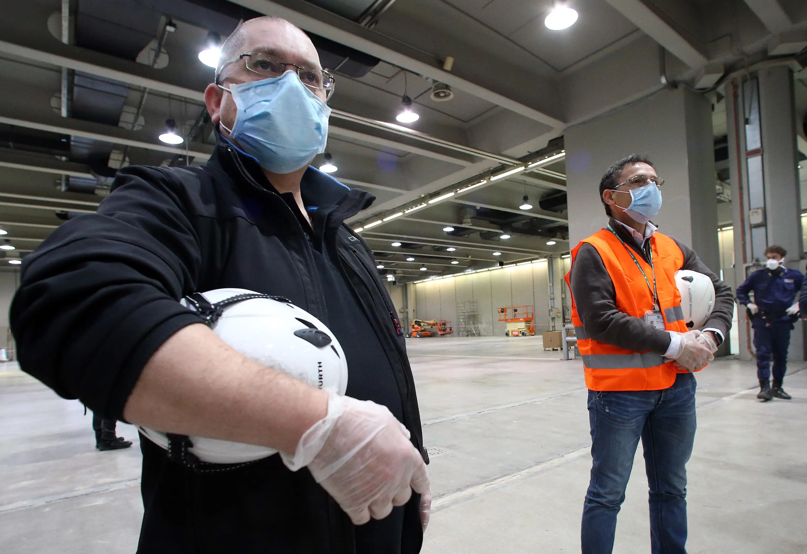 A worker and a technician wearing protective masks look at the Hall 2 of Fiera Milano City where the Lombardy region wants to set up a temporary hospital to counter the health emergency due to Coronavirus, Milan, Italy, 16 March 2020. Officials said tha the project of a temporary hospital in place of the pavilions of the Fiera di Milano on the model of those opened and now being be clesed in Wuhan, could be available within six days. Several European countries have closed borders, schools as well as public facilities, and have cancelled most major sports and entertainment events in order to prevent the spread of the SARS-CoV-2 Coronavirus causing the Covid-19 disease ANSA / MATTEO BAZZI