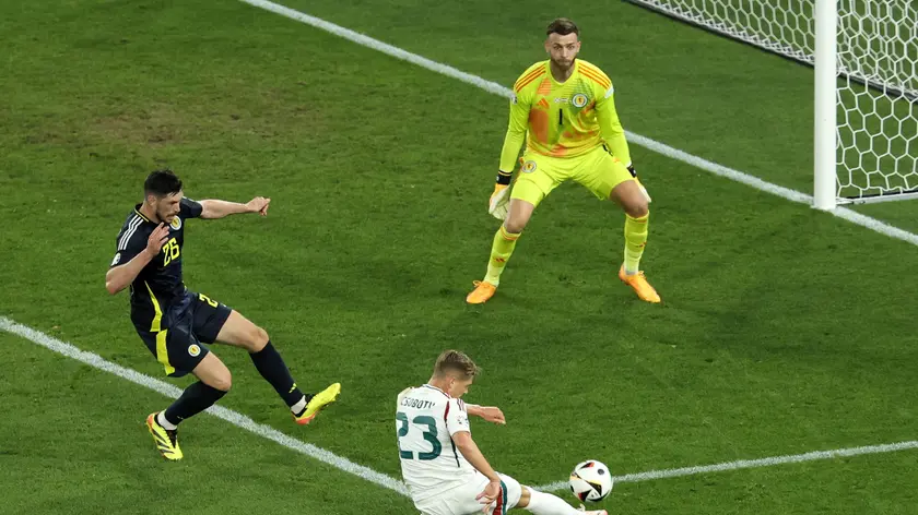 epa11433223 Kevin Csoboth of Hungary (C) in action on target against goalkeeper Angus Gunn (R) and Scott McKenna of Scotland during the UEFA EURO 2024 Group A soccer match between Scotland and Hungary, in Stuttgart, Germany, 23 June 2024. EPA/RONALD WITTEK