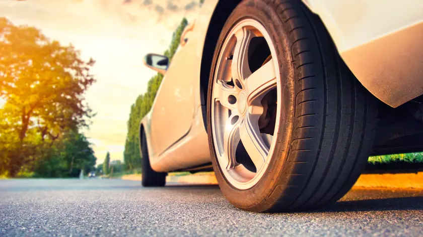 Car tire close up on asphalt road at sunset