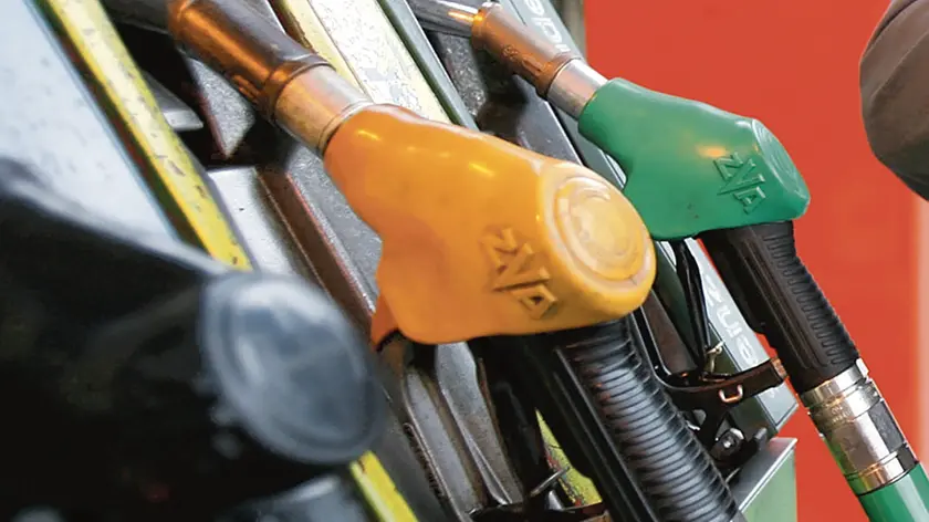 Un benzinaio incrocia le braccia davanti alle pompe di benzina in una foto d'archivio. ANSA / FRANCO SILVI