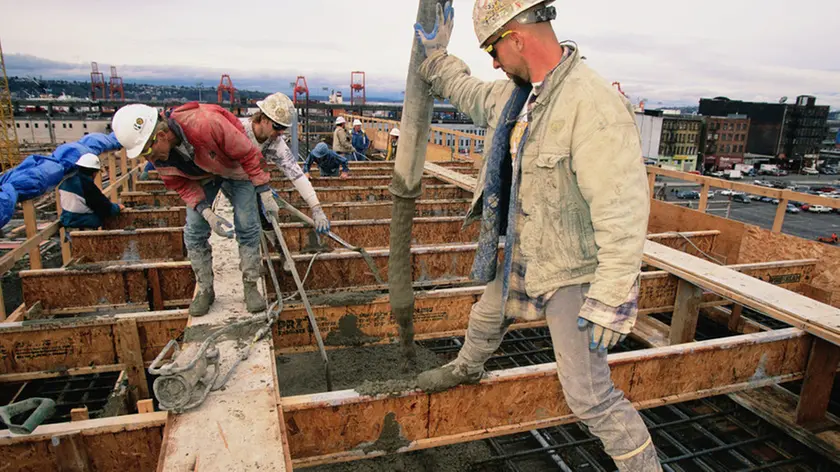 20 Feb 1998, Seattle, Washington State, USA --- Ron Vincent guides a hose to pour concrete while other construction workers smooth it out on top of the north runway at Safeco Field. --- Image by © Natalie Fobes/CORBIS