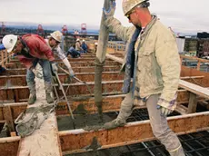 20 Feb 1998, Seattle, Washington State, USA --- Ron Vincent guides a hose to pour concrete while other construction workers smooth it out on top of the north runway at Safeco Field. --- Image by © Natalie Fobes/CORBIS