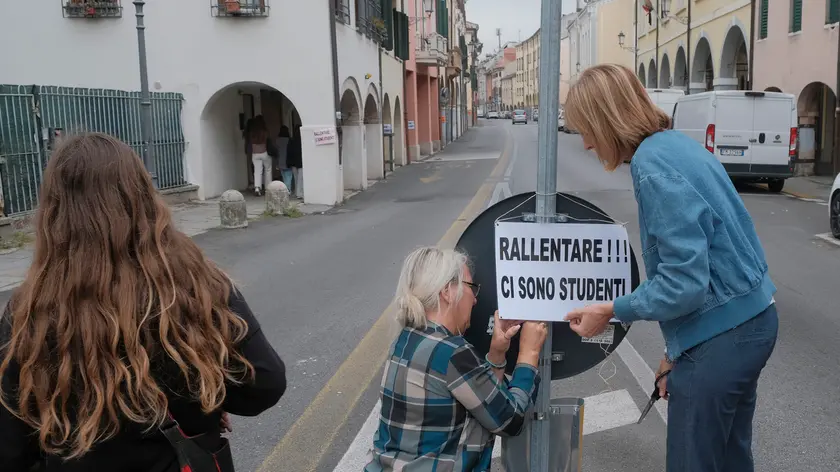 Mamme appendono cartelloni che invitano ad procedere ad agio