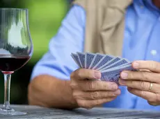 Senior man playing cards and drinking red wine, close_up