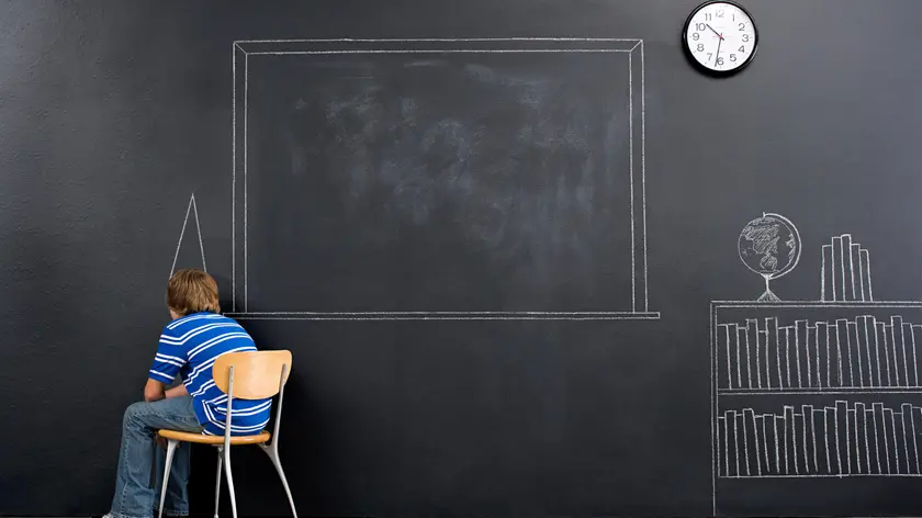 A boy sat in a corner with a chalk dunce cap
