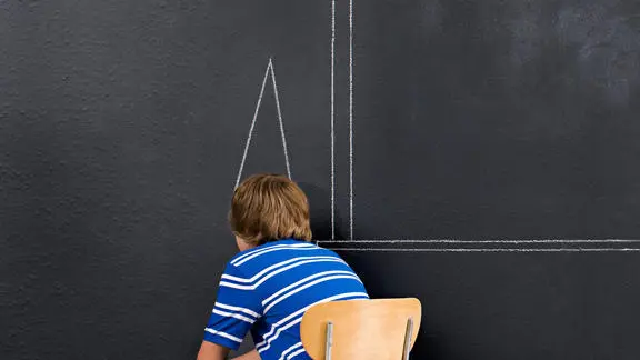 A boy sat in a corner with a chalk dunce cap