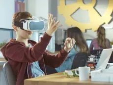 In a Computer Science Class Boy Wearing Virtual Reality Headset Works on a Programing Project.