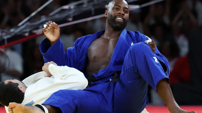 epa11519328 Temur Rakhinov of Tajikistan (white) and Teddy Riner of France (blue) in action during their Men +100kg Semifinal bout of the Judo competitions in the Paris 2024 Olympic Games, at the Champs-de-Mars Arena in Paris, France, 02 August 2024. EPA/DANIEL IRUNGU