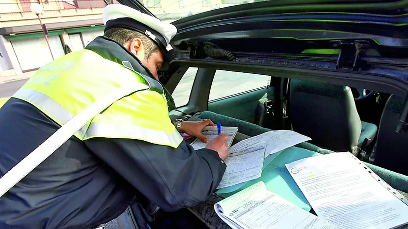 Un agente di polizia municipale impegnato a redigere un verbale a carico di un automobilista che ha violato il Codice della Strada