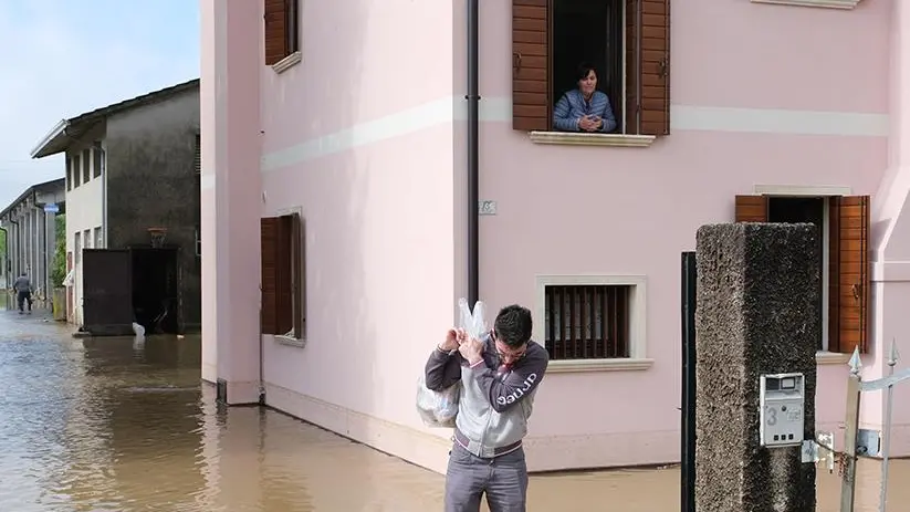 Un residente impegnato a trasportare sacchi in seguito alla rottura del Muson dei Sassi tra Camposampiero e Massanzago